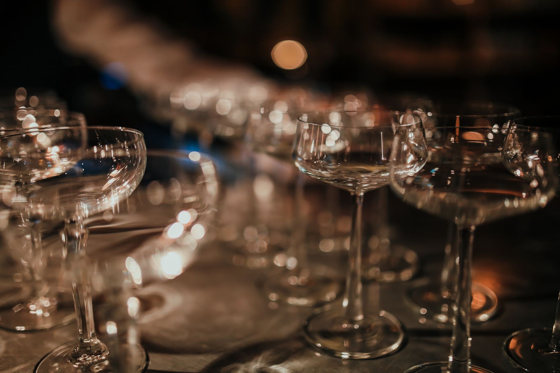 A line up of empty glasses in a restaurant. Indoor shot, artificial light. Horizontal image 